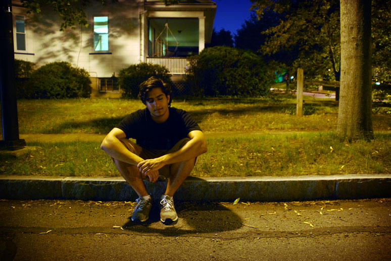 ben sitting on the sidewalk at night time